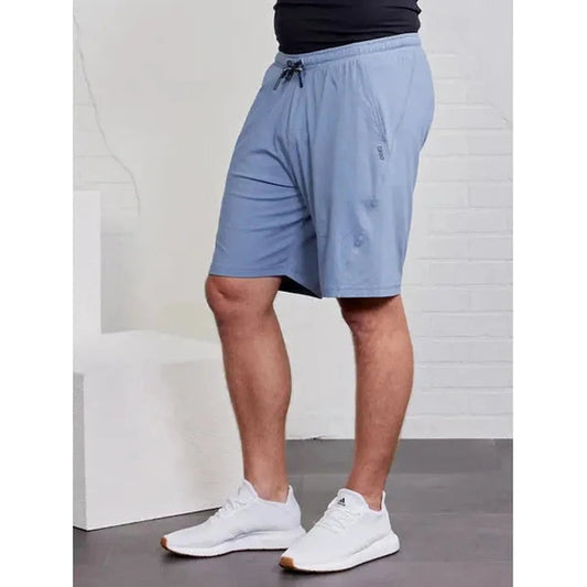Side view of the Tasc Men's Carrollton Classic Short in Anchor showing the drawstring waist and model wearing them against a white brick background.
