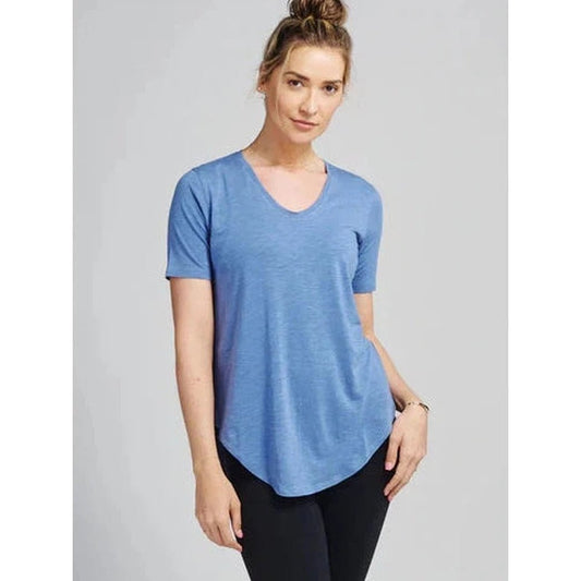 A woman wearing the Tasc Women's Longline Tee in Black Slub stands against a plain gray background.