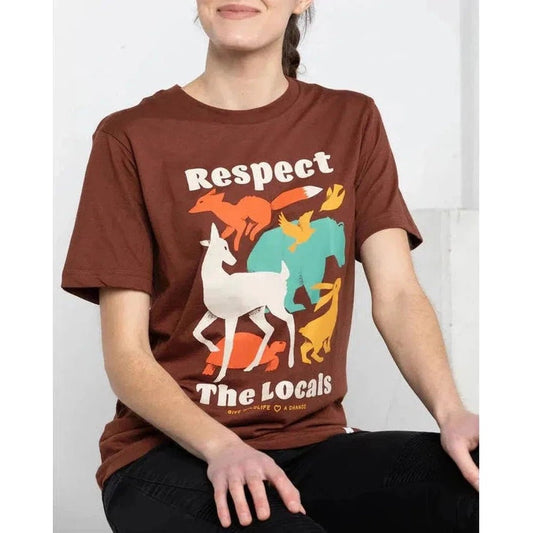A woman wearing a Redwood The Landmark Project Respect the Locals Tee sits against a white background.