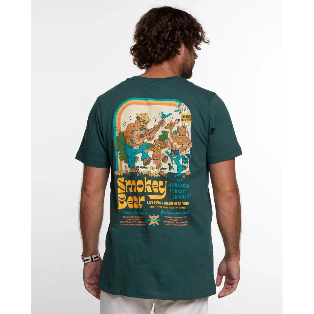Back view of The Landmark Project Smokey's Band Unisex Short Sleeve Tee in Spruce on a model against a white background.
