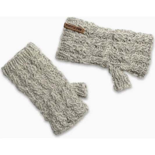 A top-down view of the Turtle Fur Nepal Handmade Wool Mika Fingerless Mittens in Black, showing the knit texture and a leather tag.