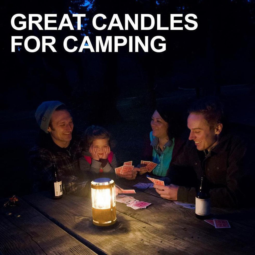 A family plays cards around a table lit by UCO Beeswax Candles - 3 Pack in a dark outdoor setting.