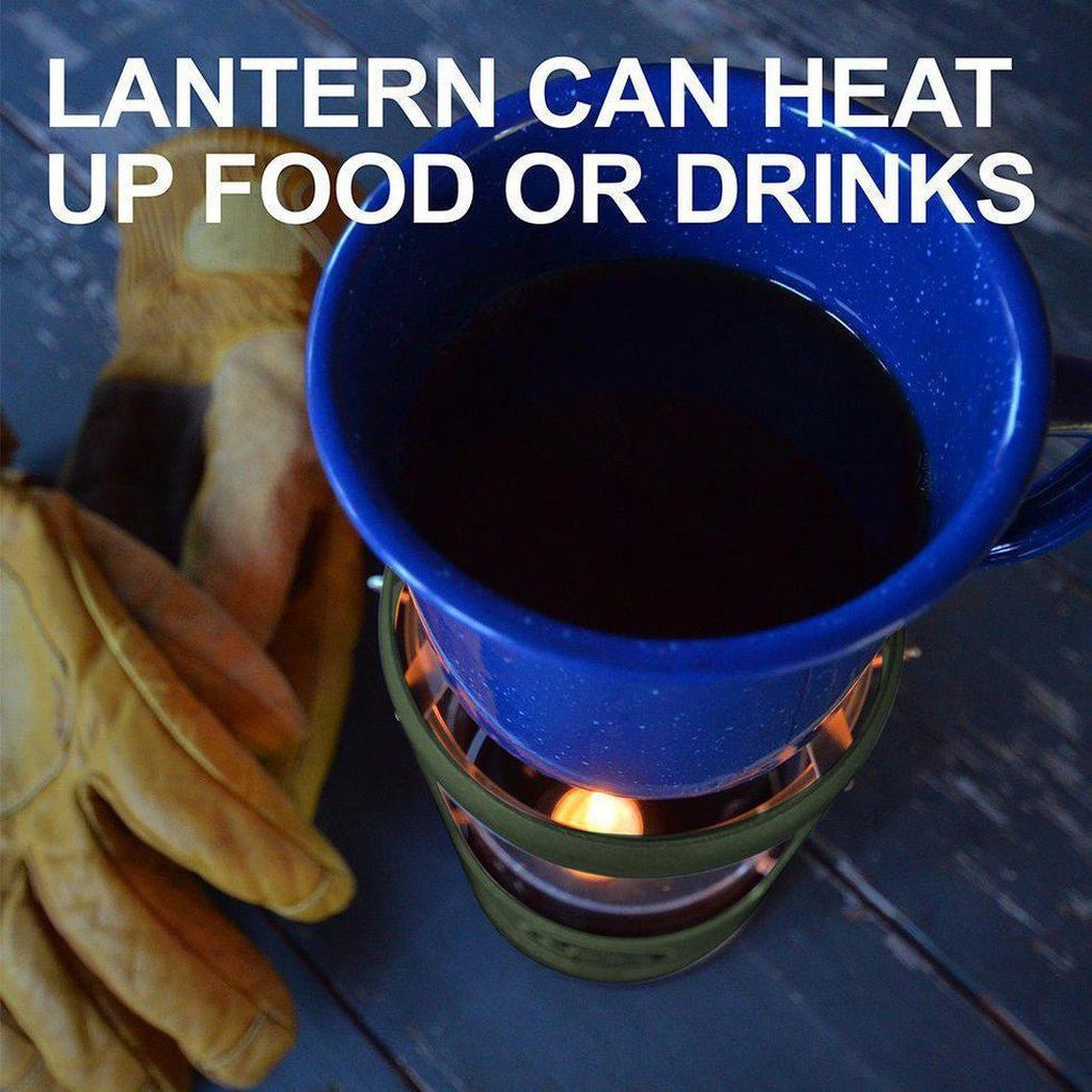 A green UCO Candlelier heats a blue mug of dark liquid on a wooden surface with leather gloves nearby.