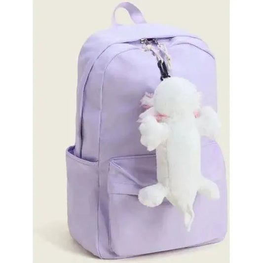 A light purple backpack with a front pocket and a white Warmies Axolotl Bag Charm hanging from the zipper, photographed from the front against a plain background.