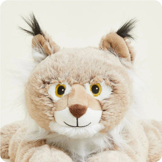 A close-up of the Warmies Bobcat plush toy with bright yellow eyes and black tufts on its ears against a plain white background.