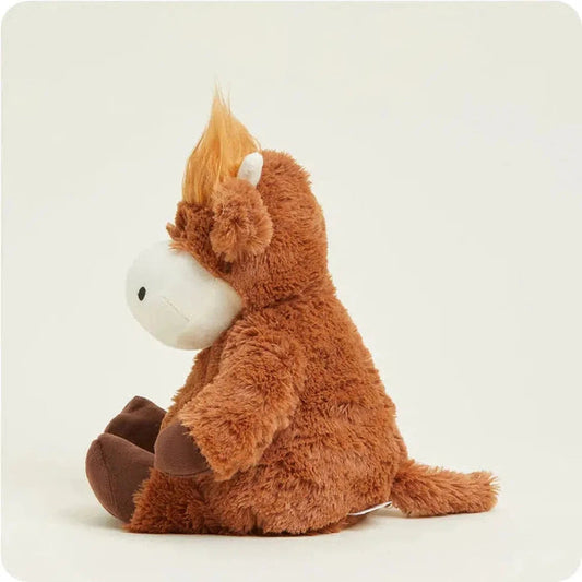Side view of the Warmies Highland Cow plush toy with brown fur and white face against a plain white background.