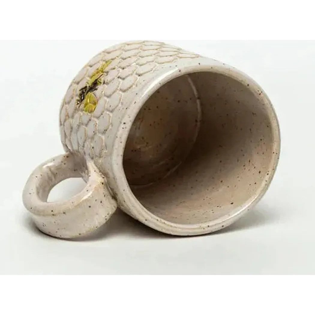 A side view of the White Squirrel Clayworks Bee Pattern Handmade in Ohio Ceramic White 10 oz Mug showing the textured exterior and open interior against a white background.