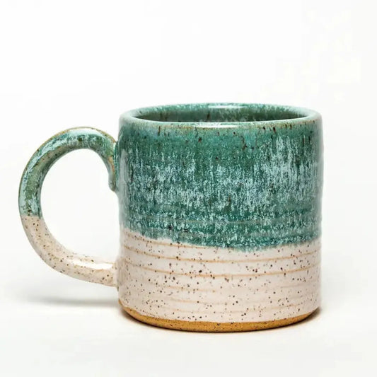 A front view of the White Squirrel Clayworks Turquoise Hand-Thrown Ceramic Mug with a turquoise upper and speckled lower section against a white background.