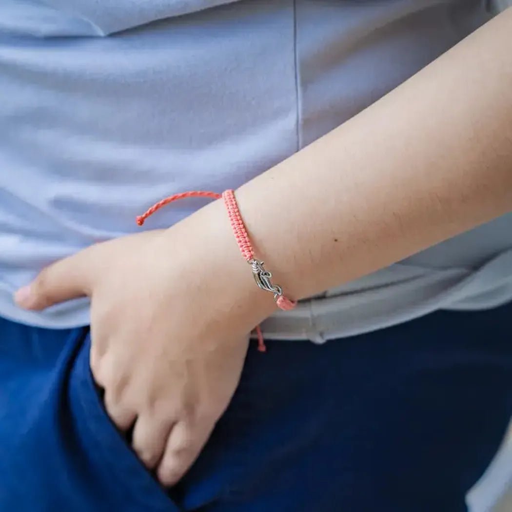 A close-up of the 4Ocean Adopt a Manatee Bracelet in Zelda on a model's wrist with blue pants and a light blue shirt.