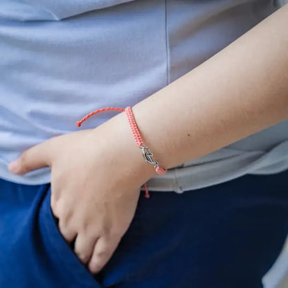 A close-up of the 4Ocean Adopt a Manatee Bracelet in Zelda on a model's wrist with blue pants and a light blue shirt.