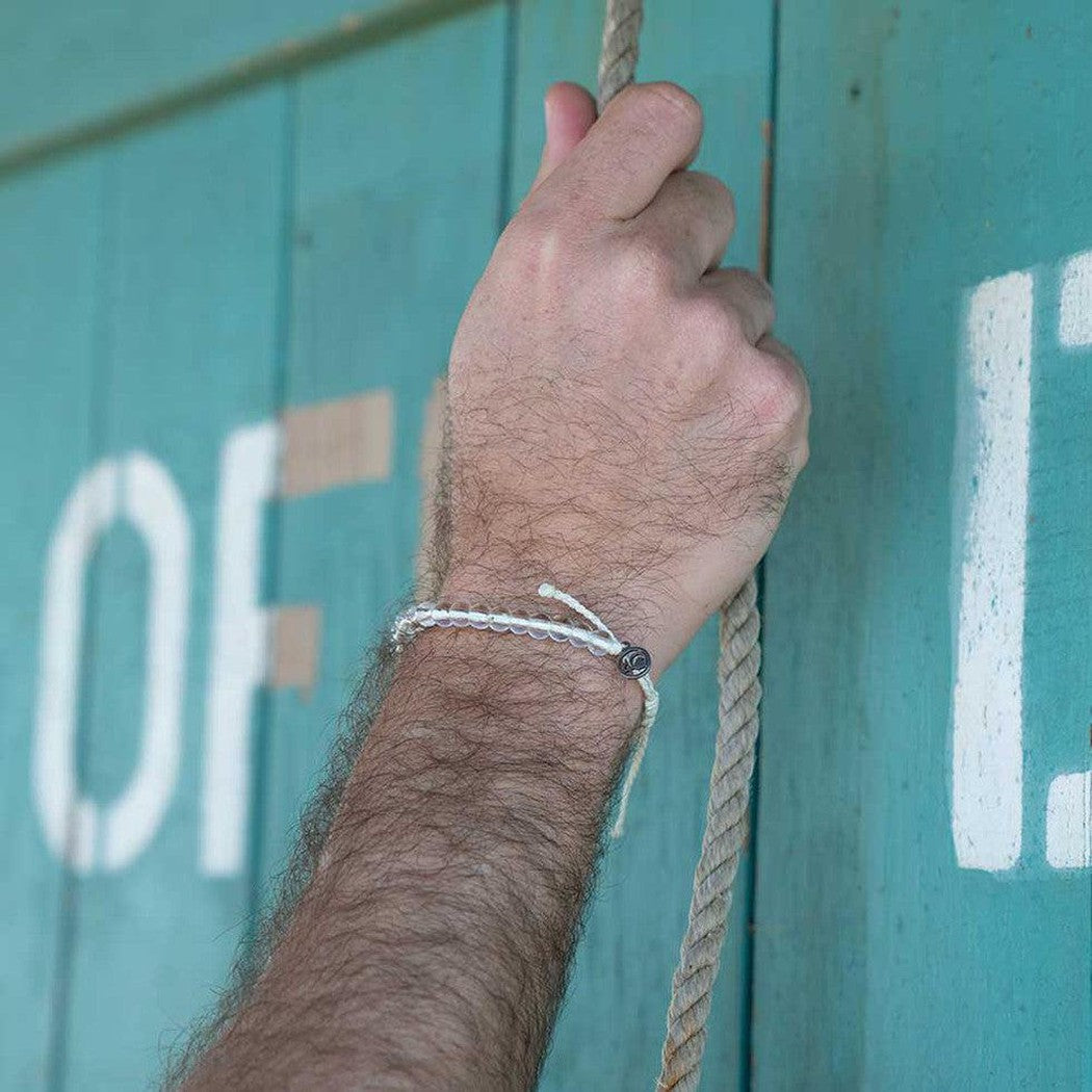 A hand gripping a rope wears the 4Ocean Deep Sea Beaded Bracelet against a teal background with white lettering.