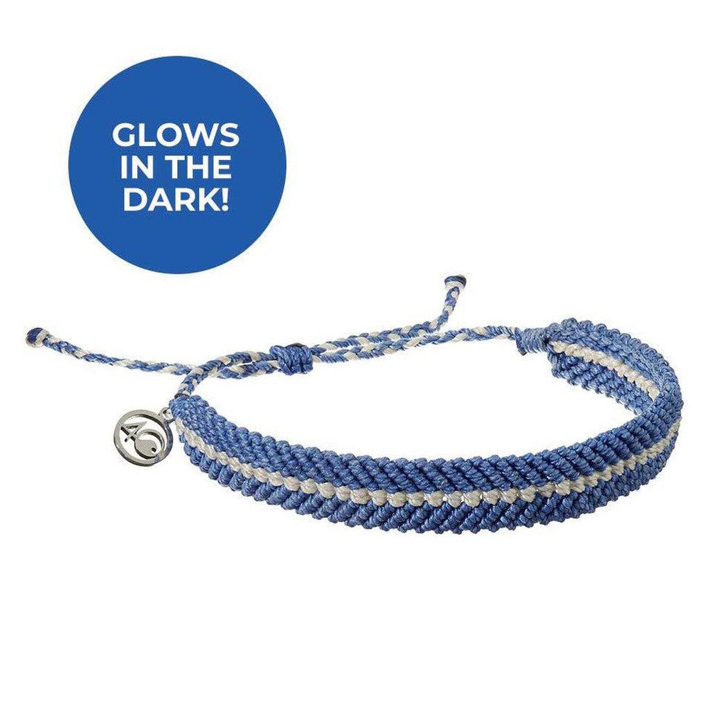 A close-up of the 4Ocean Deep Sea Beaded bracelet in Abyssal Blue Glow with a silver charm and a blue "GLOWS IN THE DARK!" circle above it.