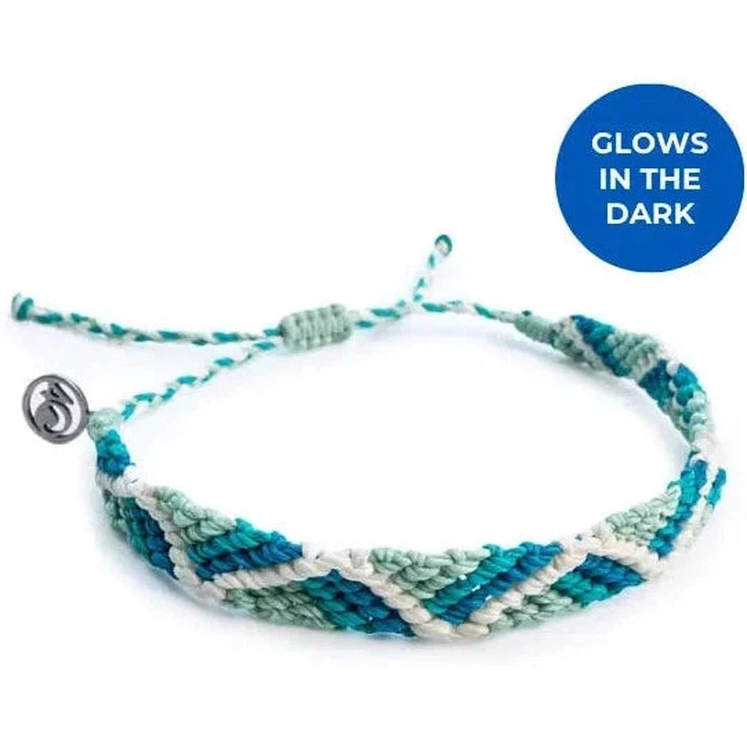 A close-up of the 4Ocean Riptide Bracelet in Mint Glow with a blue "GLOWS IN THE DARK" circle on the right.