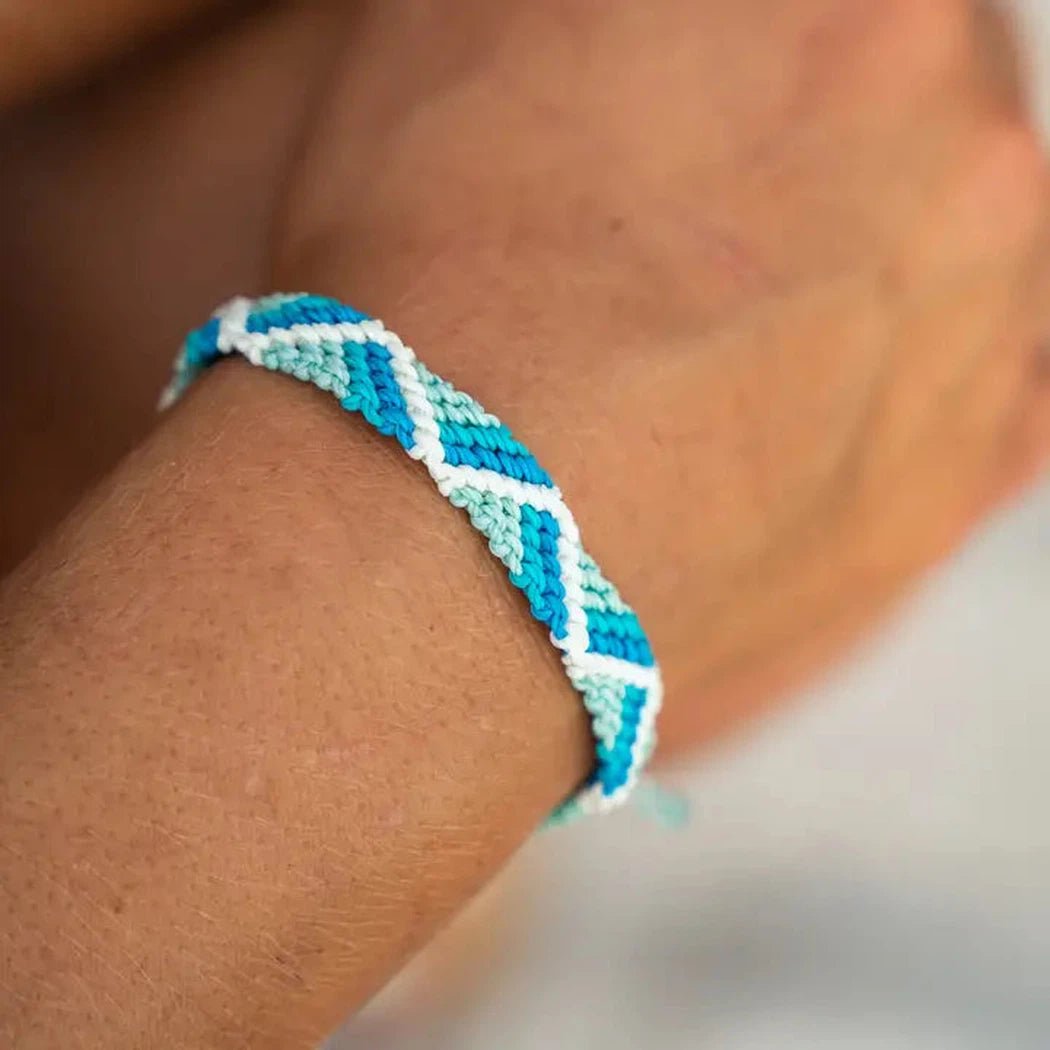 A close-up of the 4Ocean Riptide Bracelet in Mint Glow on a person's wrist with a soft background.