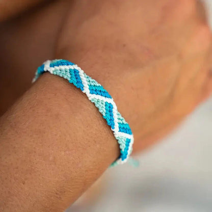 A close-up of the 4Ocean Riptide Bracelet in Mint Glow on a person's wrist with a soft background.