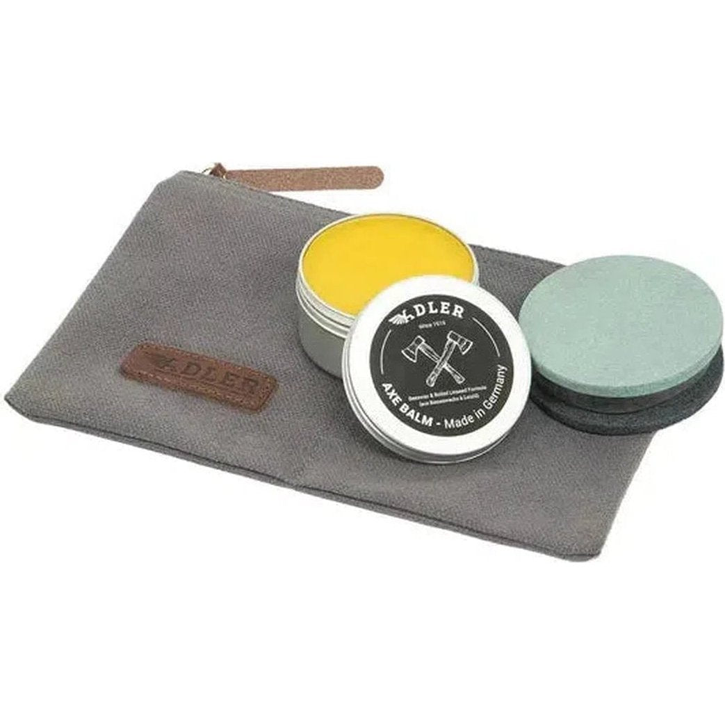 A close-up of the Adler Axe Utility Set on a gray pouch with a yellow tin, black balm, and green stone.