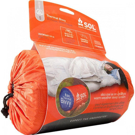A side view of the SOL Thermal Bivvy showing the orange packaging and a model wearing it.