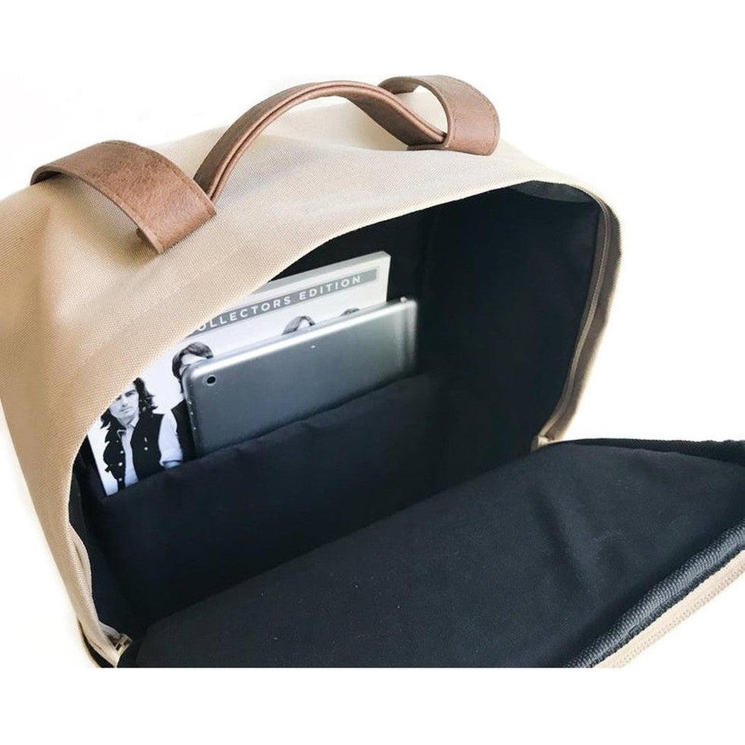 The open top of the Adobe Adventurist Backpack Co. Classic Backpack shows a tablet and a "Collectors Edition" item inside, photographed from above against a white background.