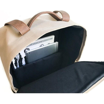 The open top of the Adobe Adventurist Backpack Co. Classic Backpack shows a tablet and a "Collectors Edition" item inside, photographed from above against a white background.