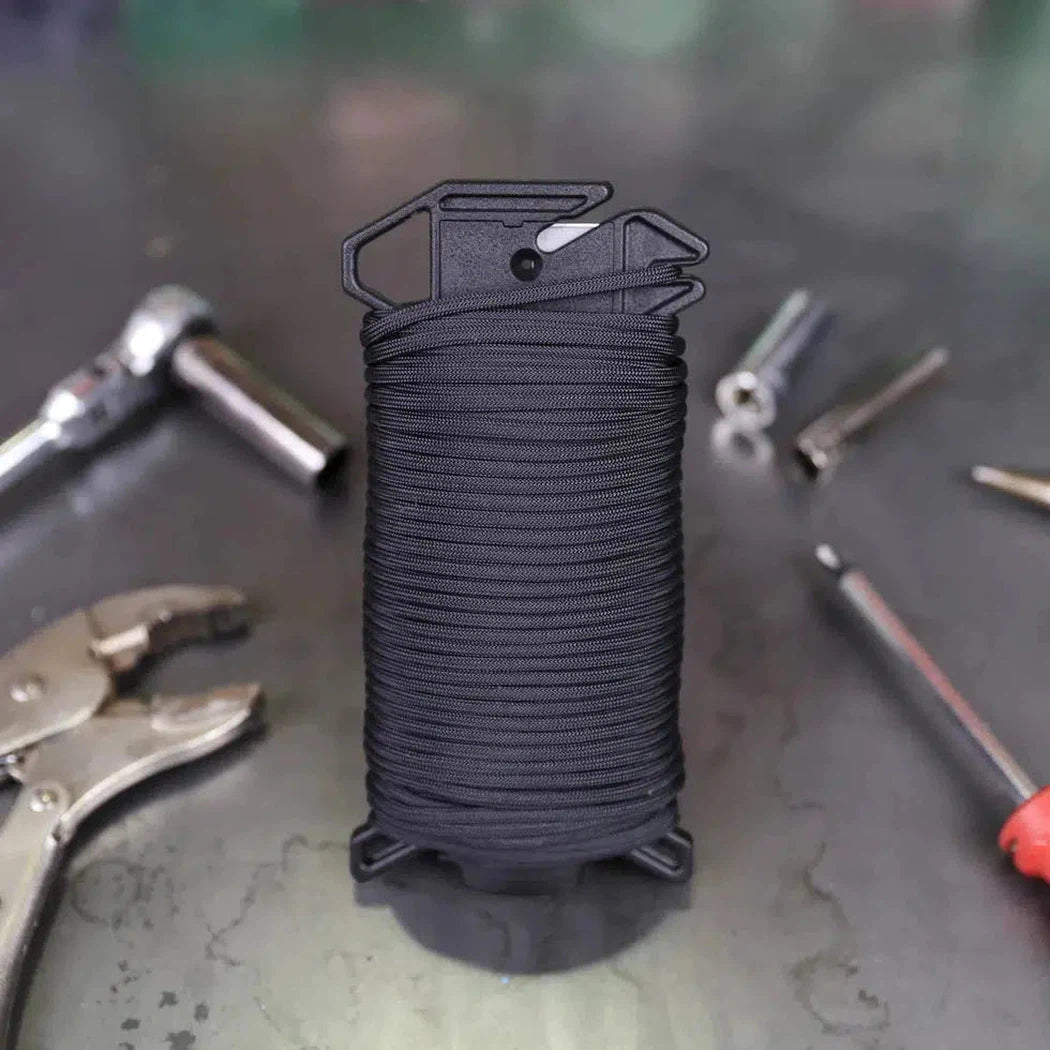A spool of black Atwood Rope Ready Rope - 550 Paracord sits on a workbench with tools around it.