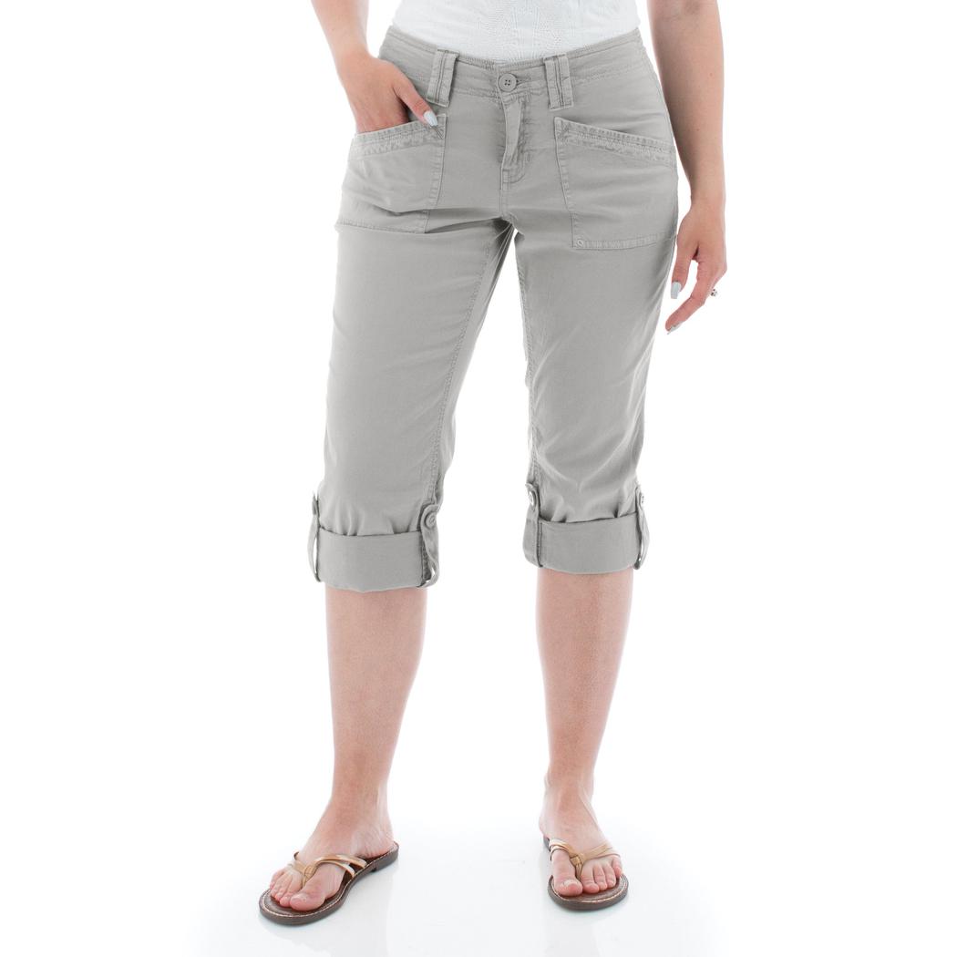 A woman wearing the Aventura Women's Arden V2 Capri in Quarry stands against a white background with rolled cuffs visible.