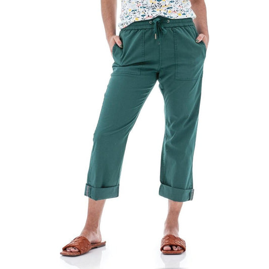 Side view of the Aventura Women's Ballard Ankle Pant in Botanical Green with rolled cuffs, model wearing brown sandals against a white background.