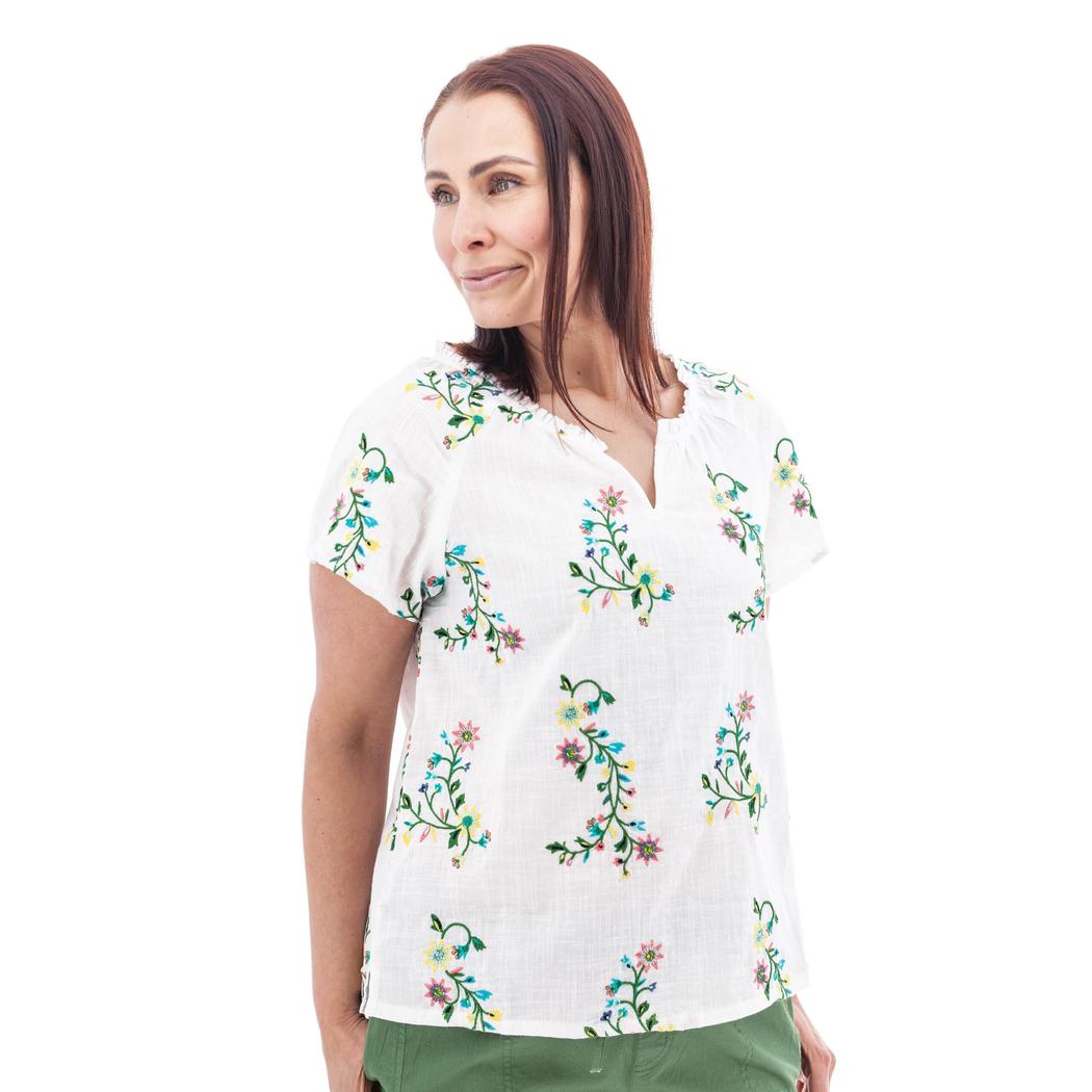 A woman wearing the Aventura Women's Lorena Top in white with floral embroidery, shown from the side against a plain white background.
