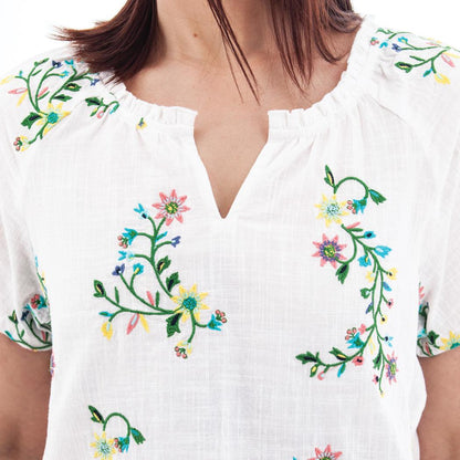 A close-up of the Aventura Women's Lorena Top in White showing the floral embroidery and V-neckline on a model.