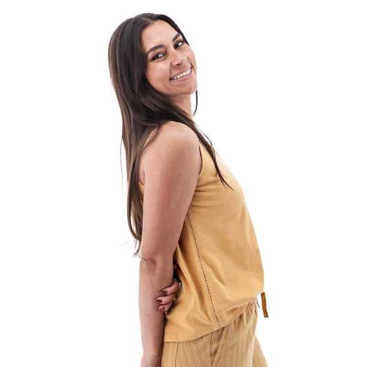 Side view of the Aventura Women's Simone Tank Top in Amber Gold showing the model wearing it against a white background.