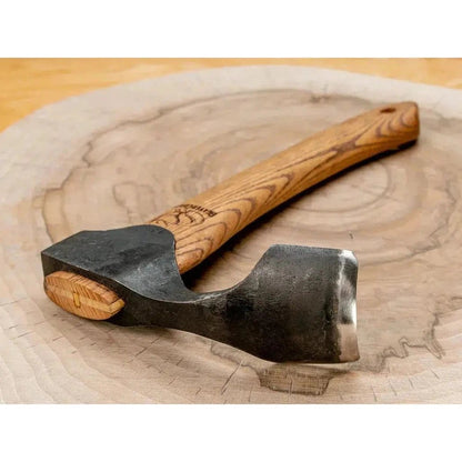 A close-up of the Beavercraft Adze with Leather Sheath on a wooden surface showing its handle and blade.