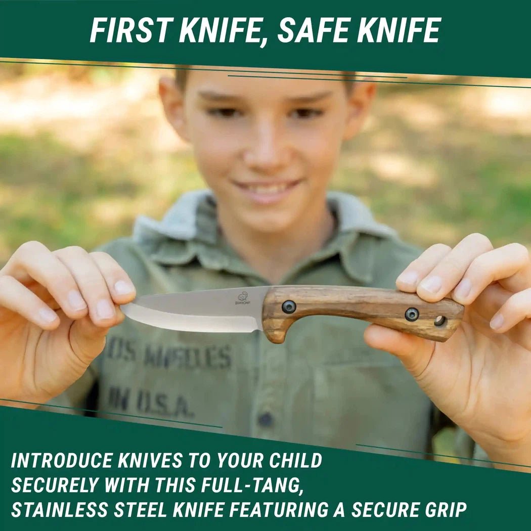 A young boy holds the Beavercraft Carbon Steel Blued-Blade Bushcraft Knife for Kids with Leather Sheath in front of a blurred outdoor background.