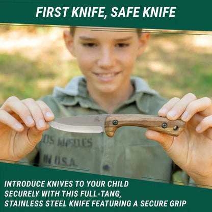 A young boy holds the Beavercraft Carbon Steel Blued-Blade Bushcraft Knife for Kids with Leather Sheath in front of a blurred outdoor background.