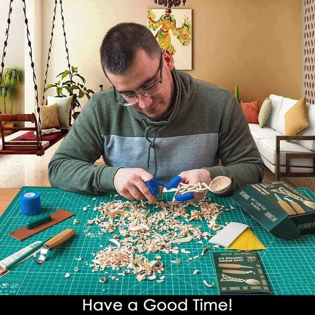 A man works on a Beavercraft Celt Spoon Carving Kit at a green cutting mat with wood shavings around him.