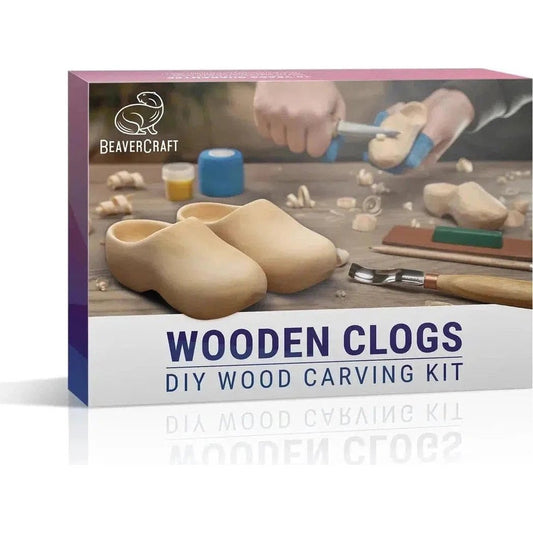 A front view of the Beavercraft Wooden Clogs DIY Wood Carving Kit box showing the finished clogs and carving tools on a workbench.