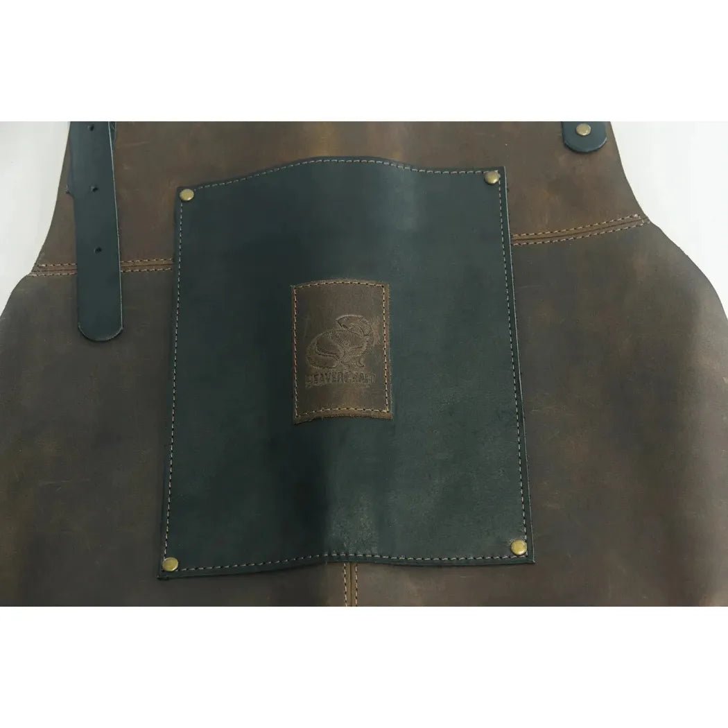 A close-up of the Beavercraft Cowhide Apron Leather showing the dark pocket panel and brass rivets against a brown leather background.