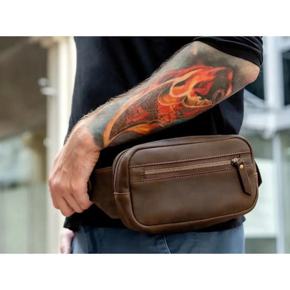 A man with a colorful tattoo on his arm wears the brown Beavercraft Quest leather waist bag in a side view.