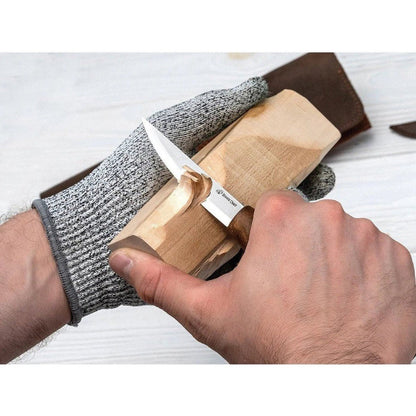 A person uses the Beavercraft Spoon Carving Tool Set in a genuine leather case on a light wooden block with a gray glove.