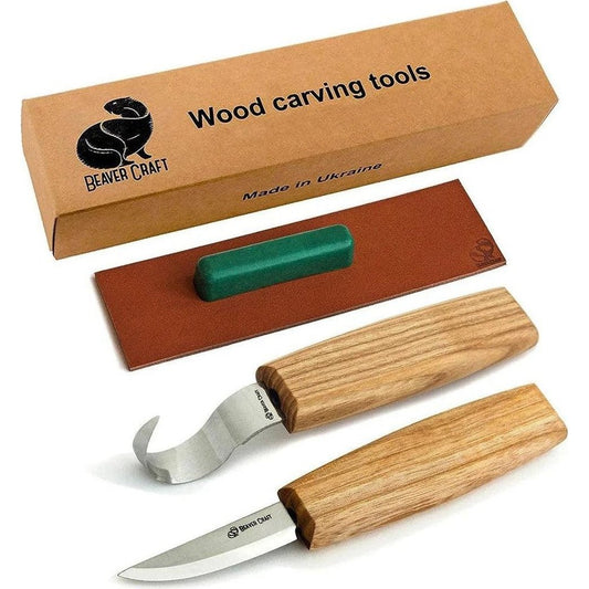 A top-down view of the Beavercraft Spoon Carving Tool Set with wooden handles and a green sharpening stone on a brown leather pad.