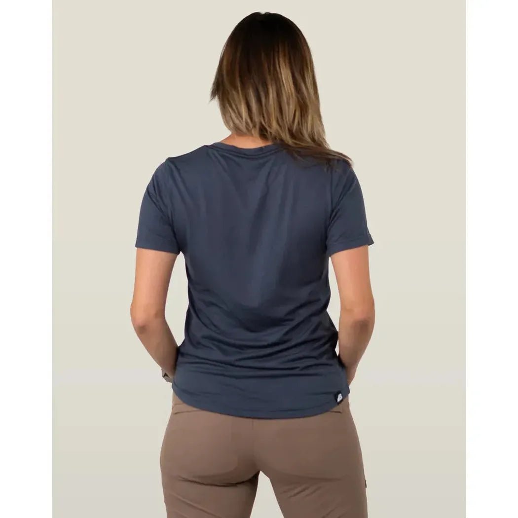 Back view of the Belong Designs Women's Core Traverse Tek Tee in Blue showing the model wearing it against a light background.