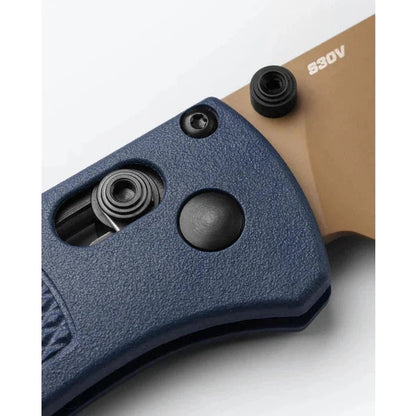Close up of the Benchmade Bugout knife with blue handle and tan blade, showing the thumb stud and pocket clip against a white background.