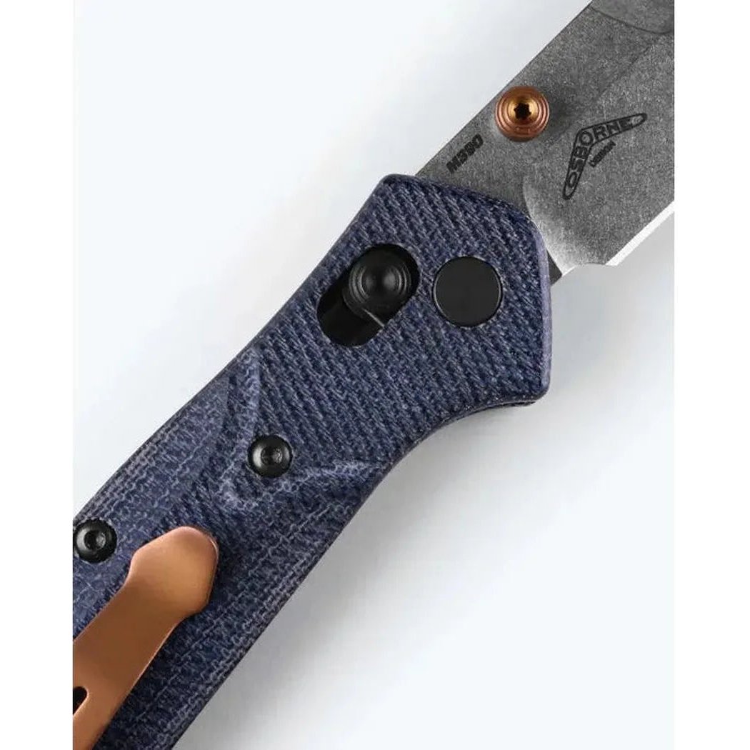 A close-up of the Benchmade Mini Osborne knife with a blue handle and copper accents, shown from a side angle against a white background.