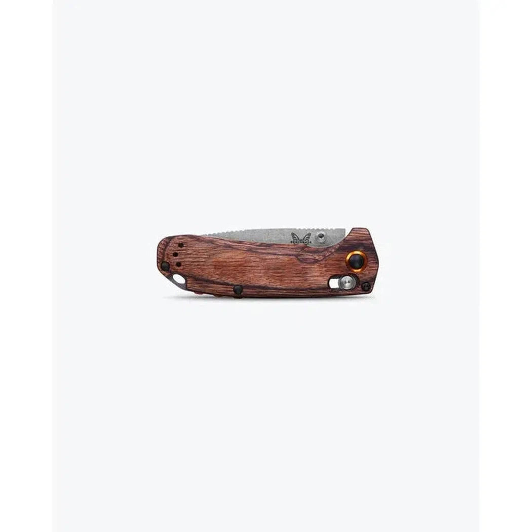 A side view of the Benchmade North Fork in Maple Stabilized Wood with a serrated blade and a wooden handle against a white background.