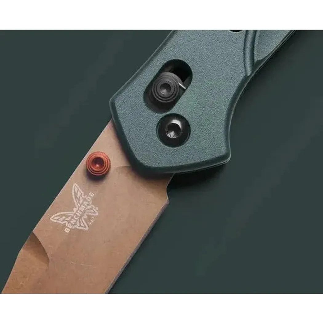 A close-up of the Benchmade Osborne knife with its charcoal/ graphite handle and tan blade, showing the butterfly logo and a red screw.