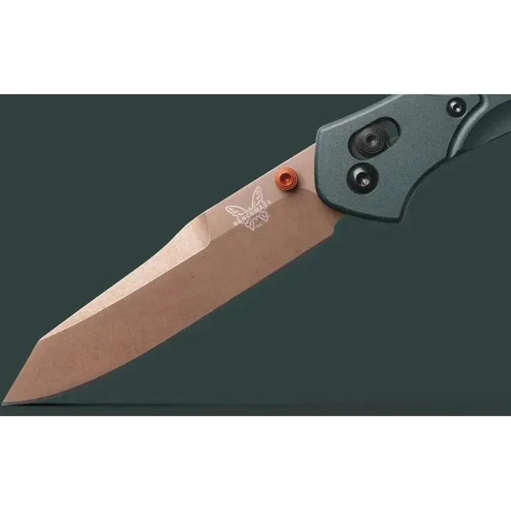 A close-up side view of the Benchmade Osborne knife with its tan blade and charcoal/gray handle, showing the butterfly logo and orange screw on a dark background.