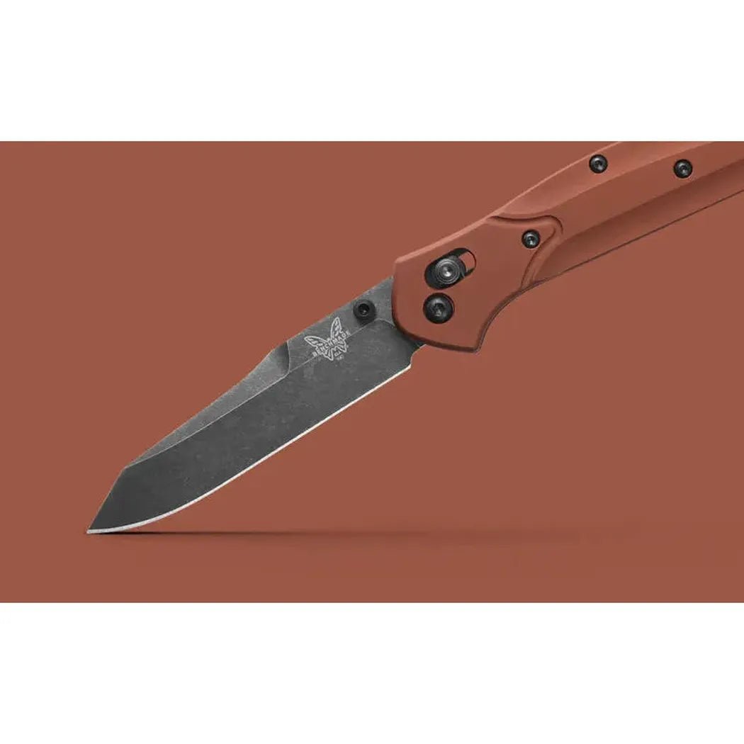 A side view of the Benchmade Osborne knife with a charcoal/graphite blade and red handle against a solid brown background.