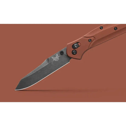 A side view of the Benchmade Osborne knife with a charcoal/graphite blade and red handle against a solid brown background.