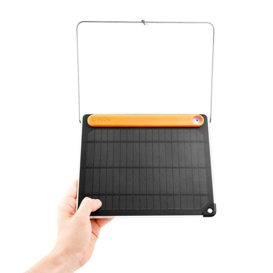 A hand holds the BioLite SolarPanel 5+ with its orange top bar and charcoal panel against a white background.
