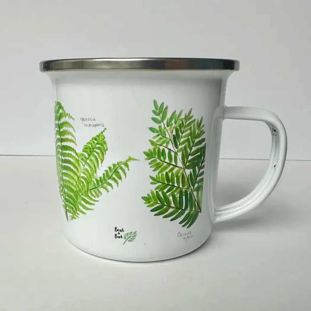 A white Brush & Bark Camping Mug with green fern designs sits on a white surface against a plain background.