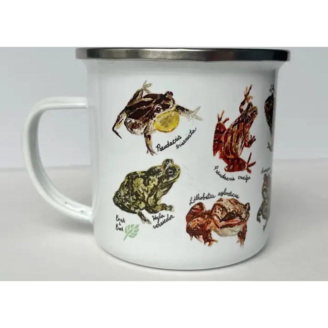 A white Brush & Bark Camping Mug with a silver rim and various frog illustrations on the side, photographed from a front angle against a plain white background.