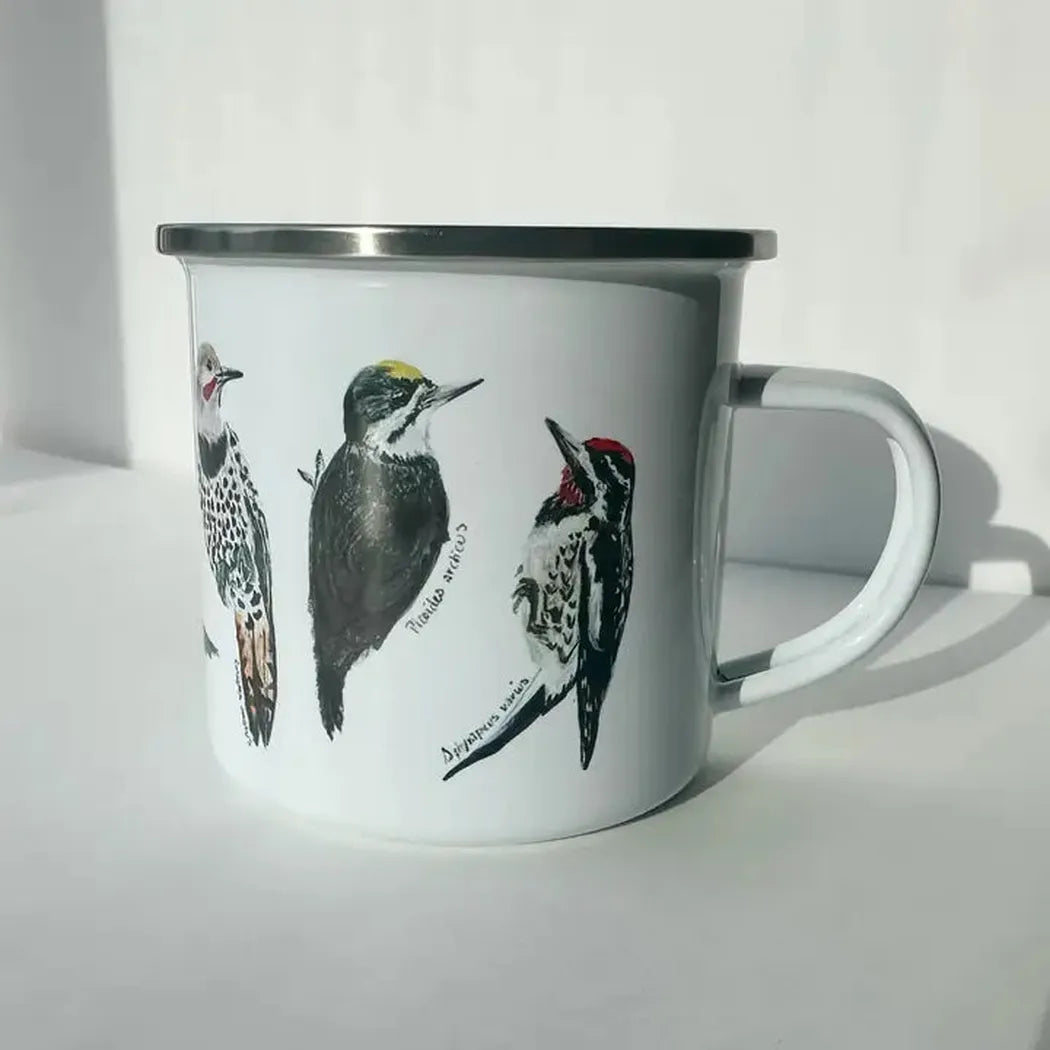 A white Brush & Bark Camping Mug with a silver rim and handle displays three Backyard Birds illustrations, photographed from a front angle against a plain white background.